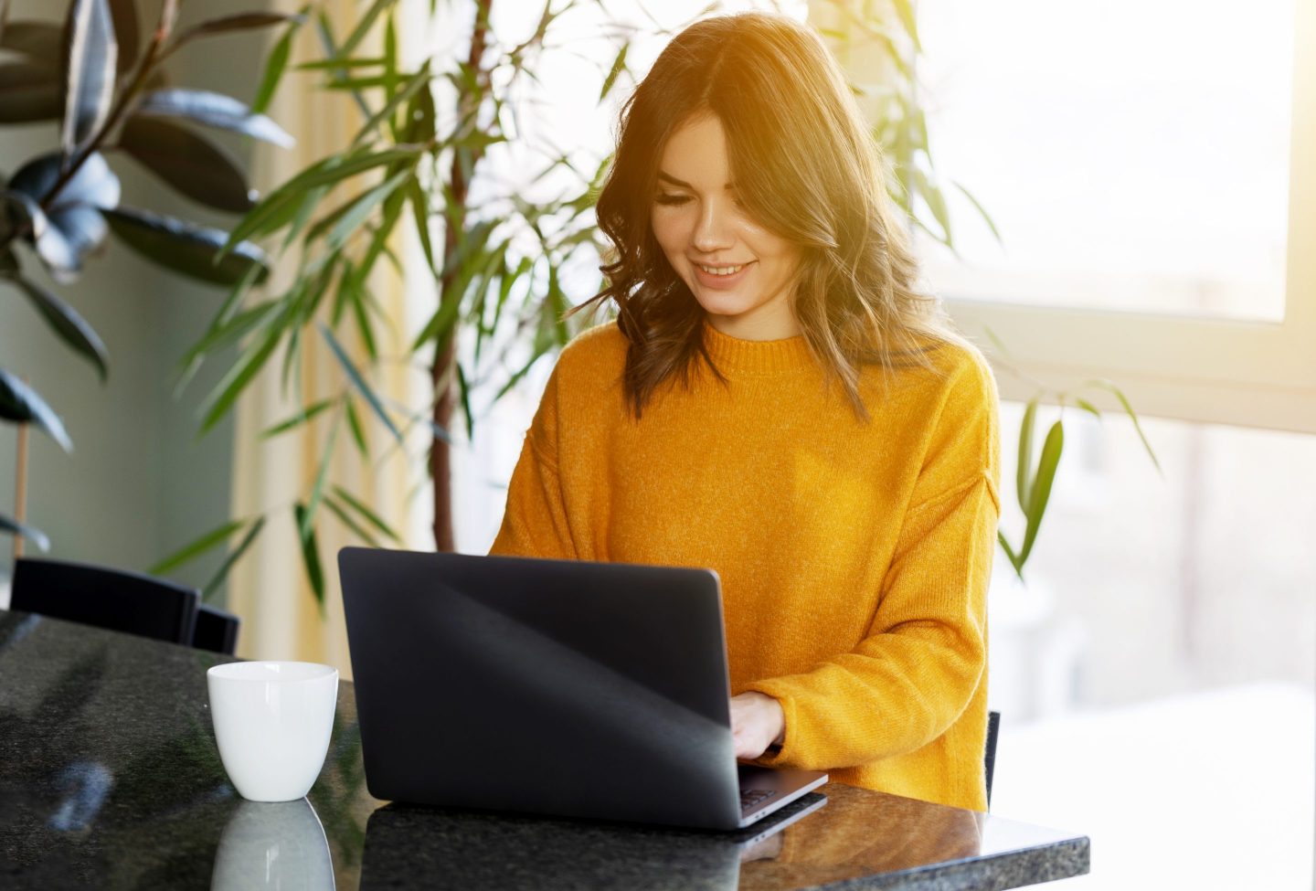 A woman wearing an orange sweater works from home