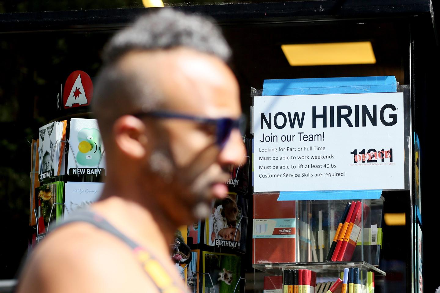 Worker in front of 'now hiring' sign