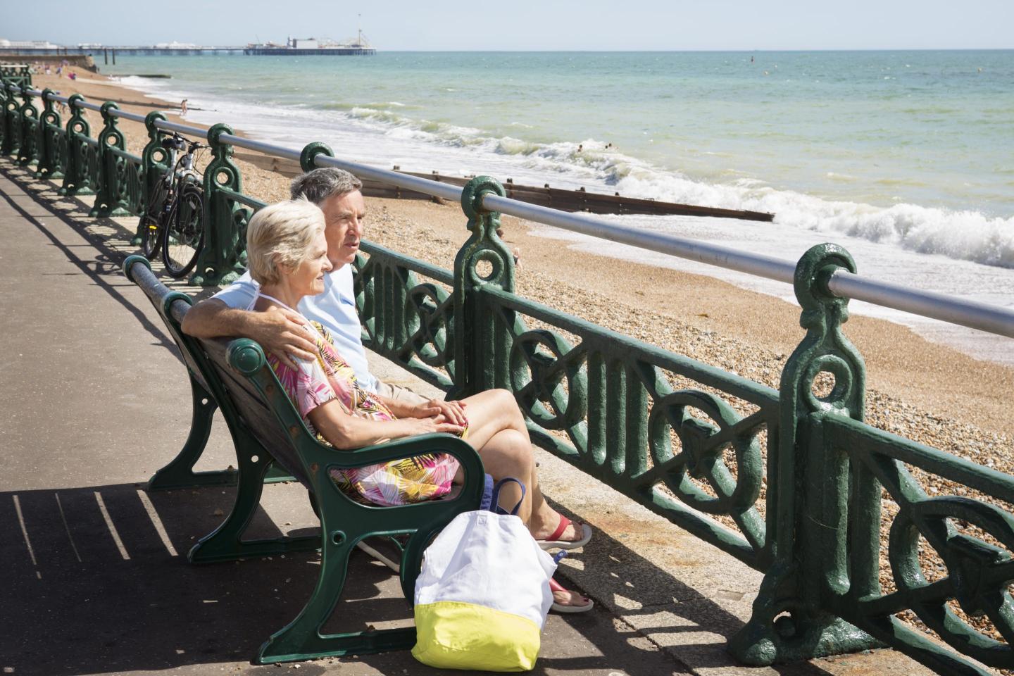Senior couple sitting on bench looking at sea.