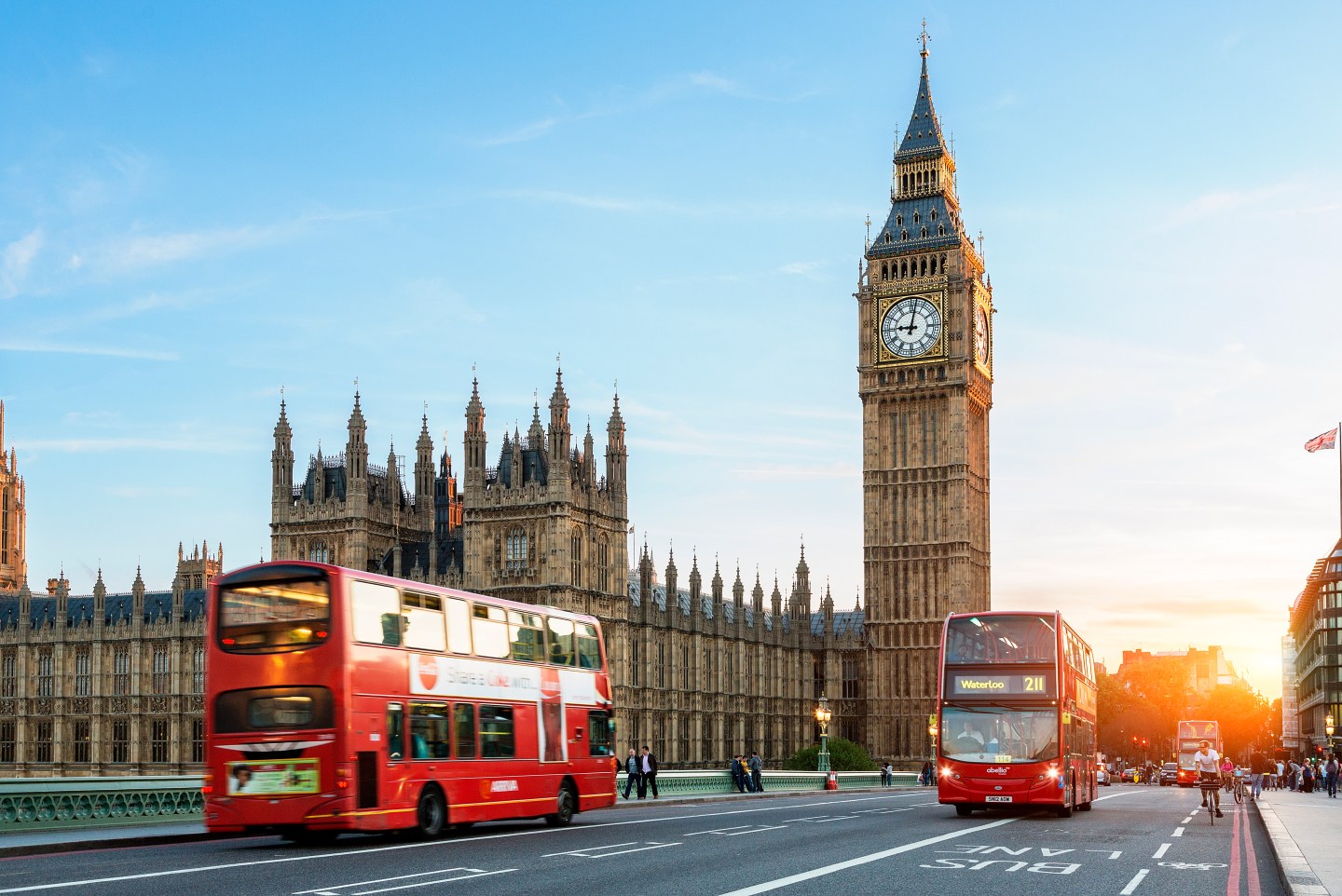 A double decker London bus riding past Big Ben.