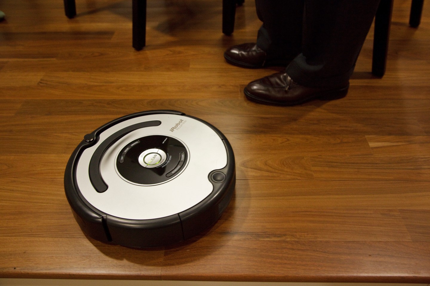 A roomba vacuum cleaner on a hardwood floor