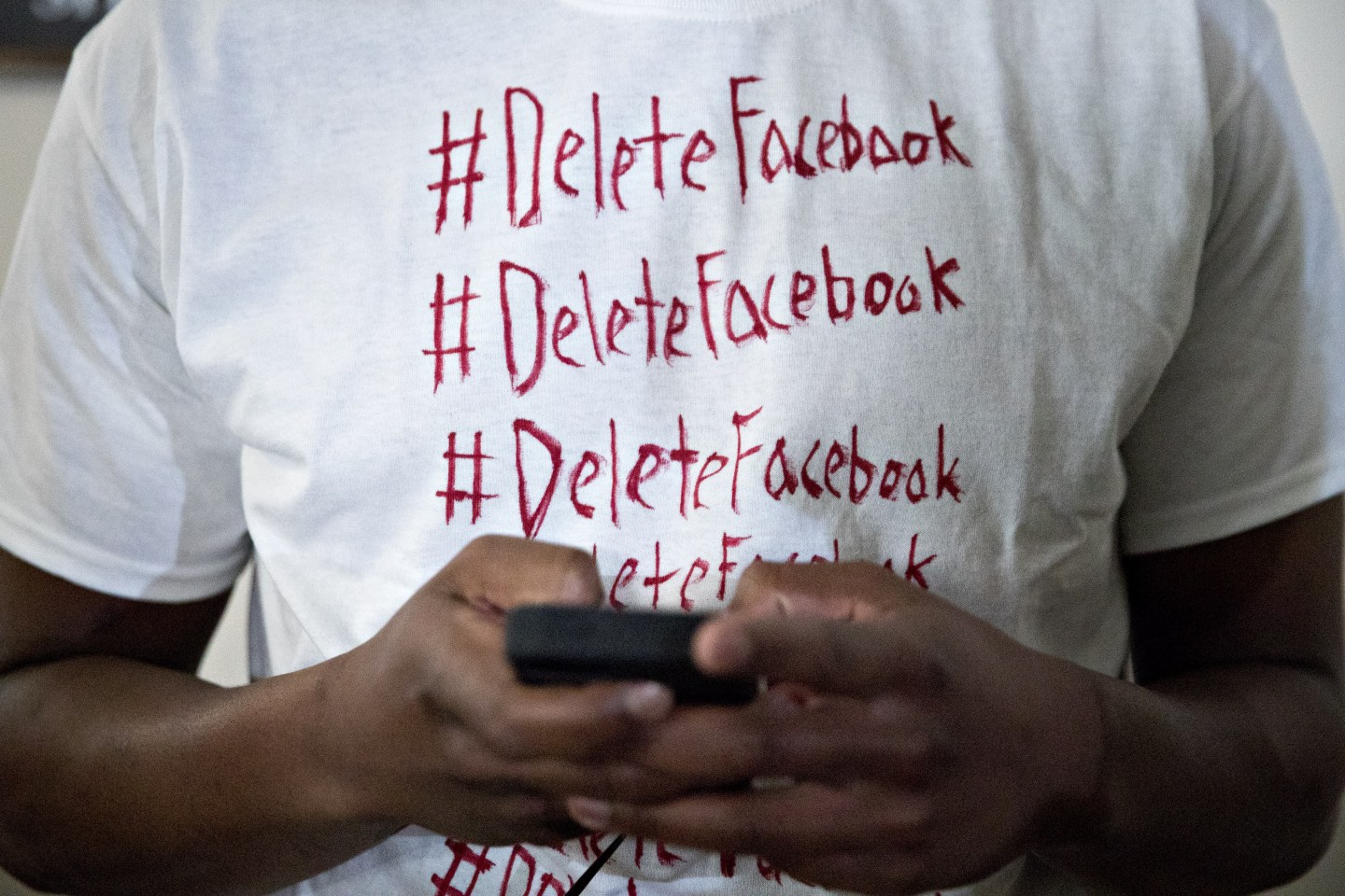 A person wearing a shirt that reads #DeleteFacebook