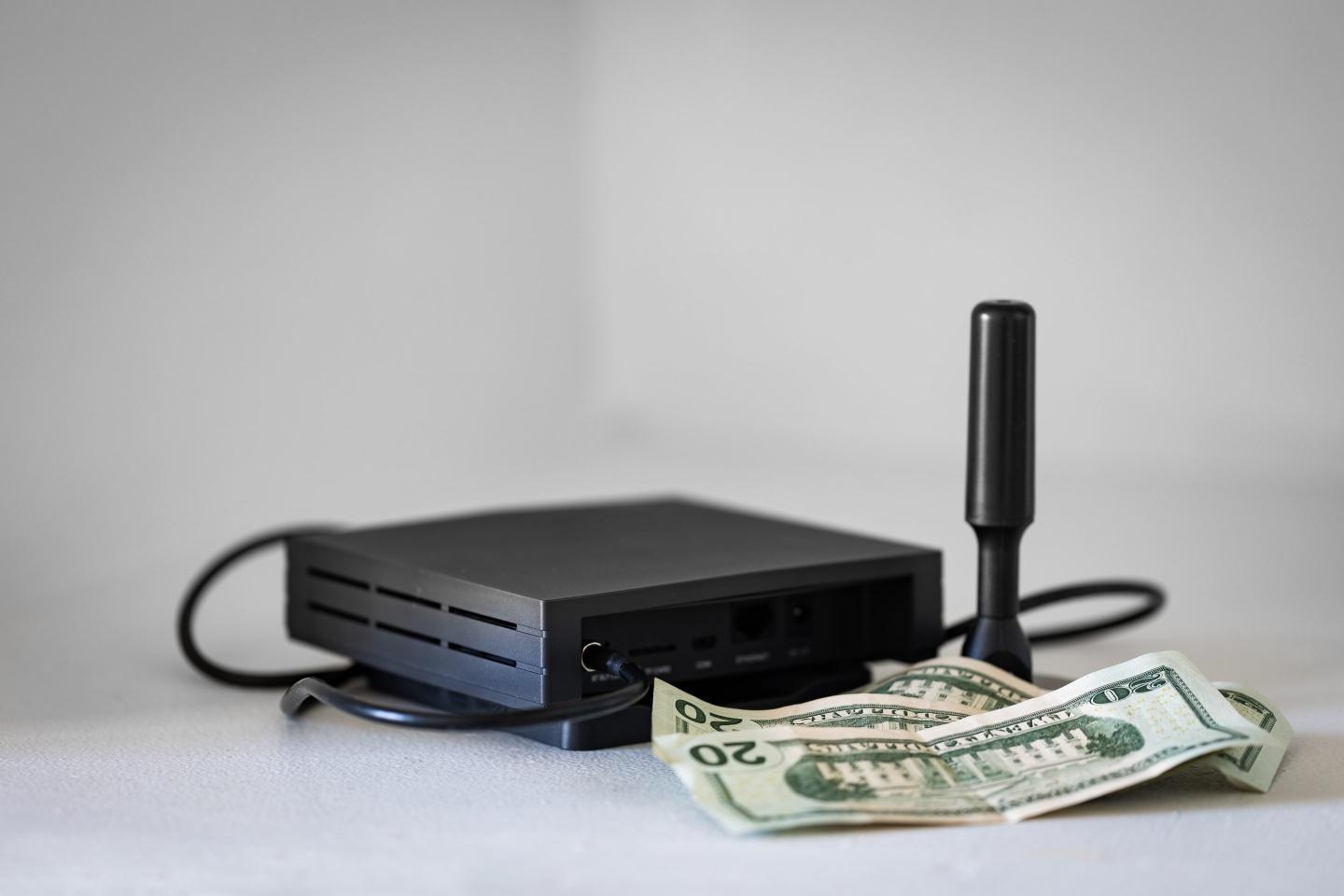 HNT cryptocurrency miner hotspot with antenna for radio connection and dollar bills as an association with profits from blockchain mining