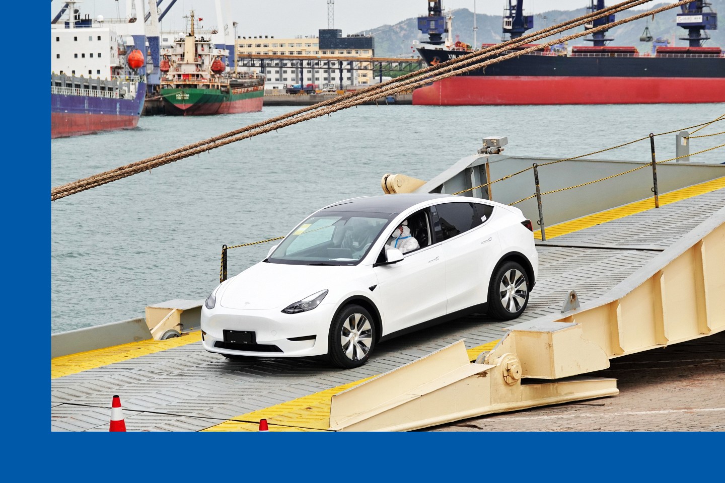 A driver in PPE moves a new Tesla passenger car from Shanghai off a ship in the port in Yantai in east China's Shandong province on April 25, 2022