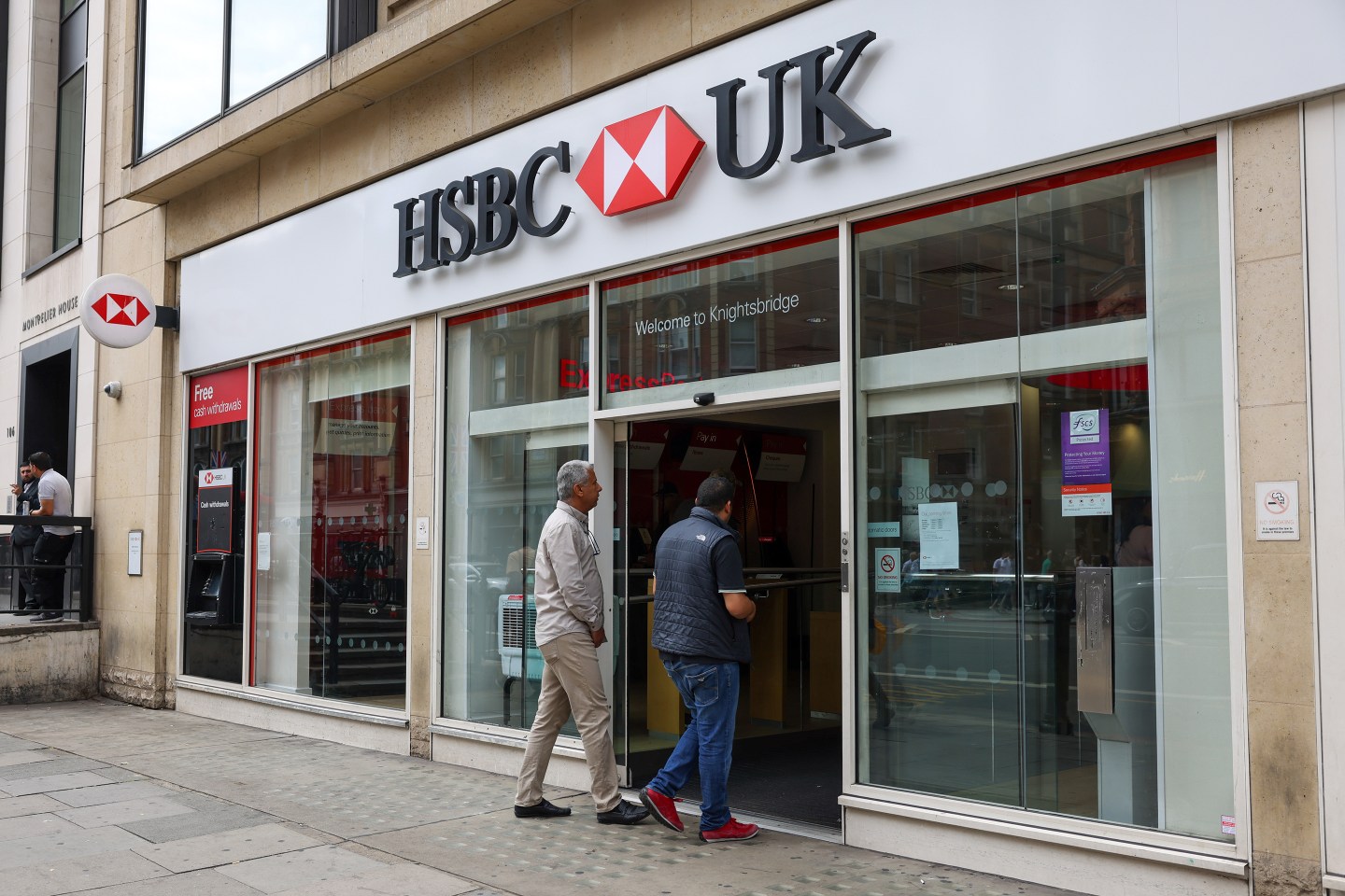 Pedestrians pass a HSBC Holdings Plc bank branch.