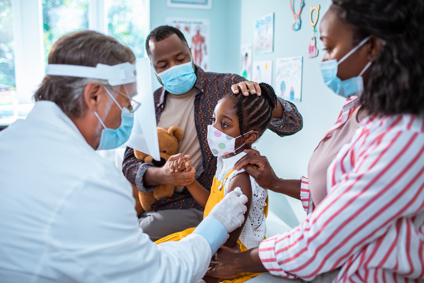 Black family wearing masks sitting in doctor's office with doctor.