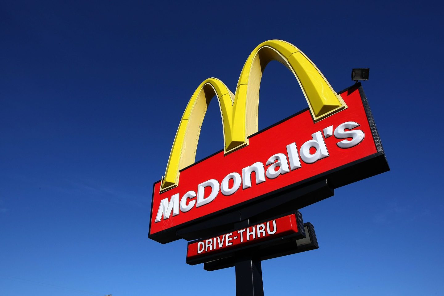 A McDonald's sign with the golden arches stands outside of a McDonald's restaurant