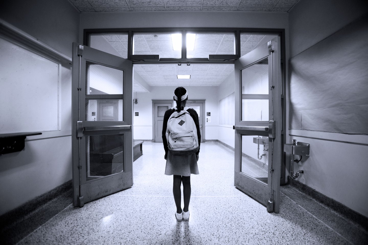 a tween aged girl looking down school corridor.