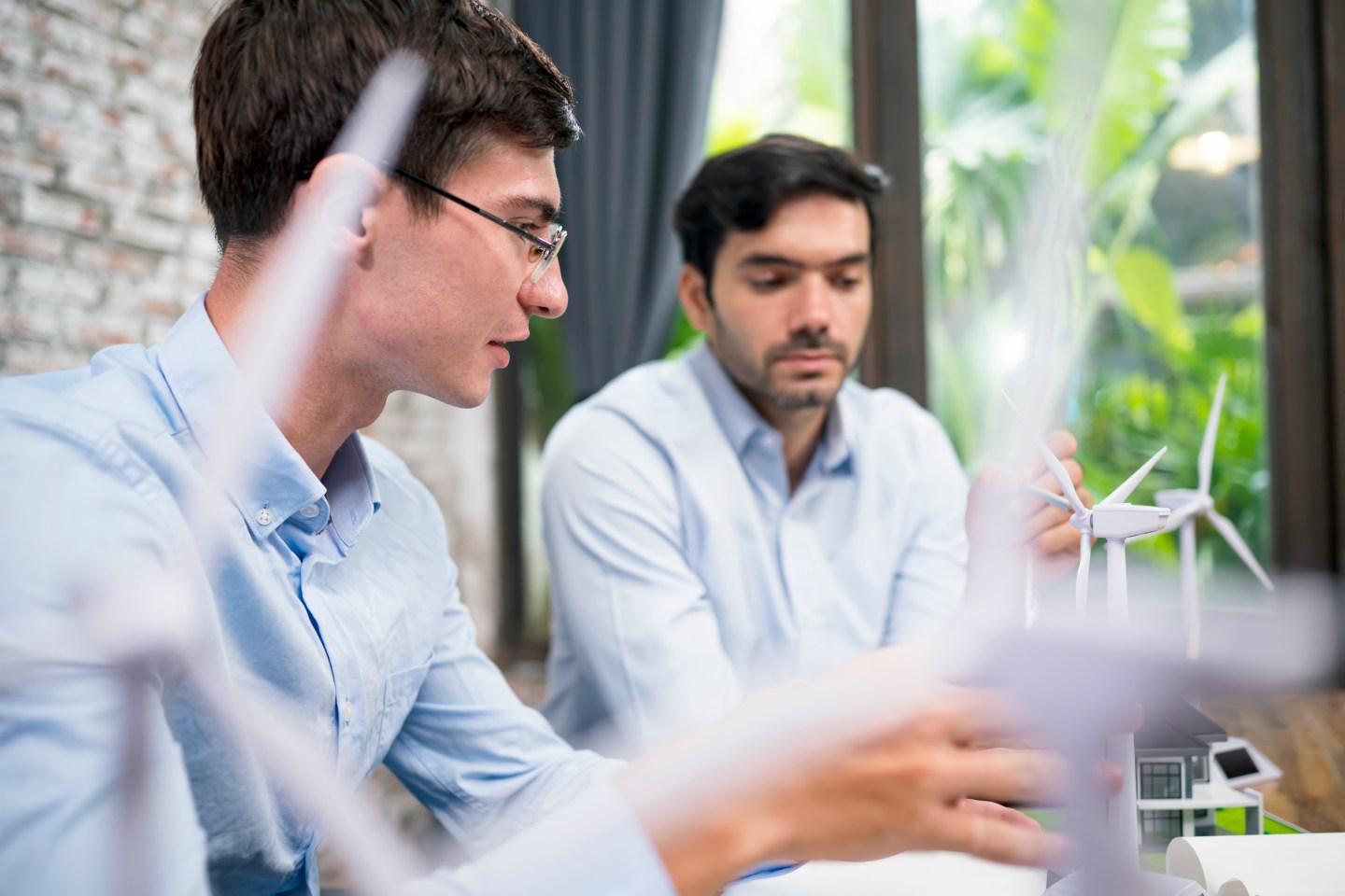Two workers looking at model wind turbines.