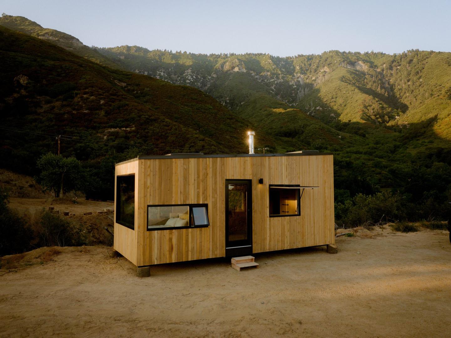 A small wooden cabin in front of a mountain range