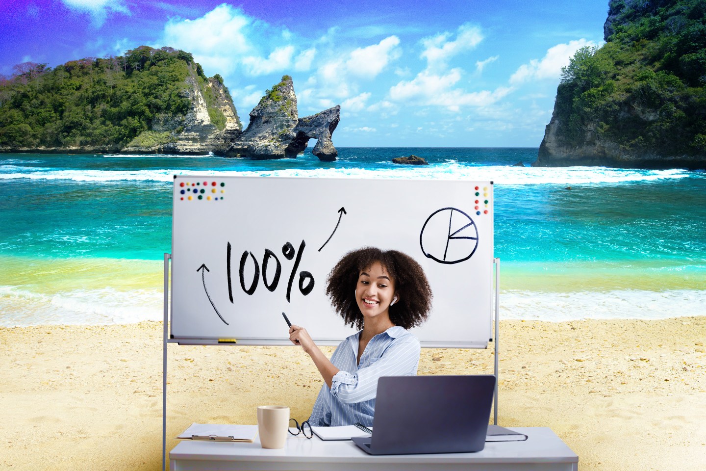 a woman sits at a desk on the beach and points to a white board while looking at a computer
