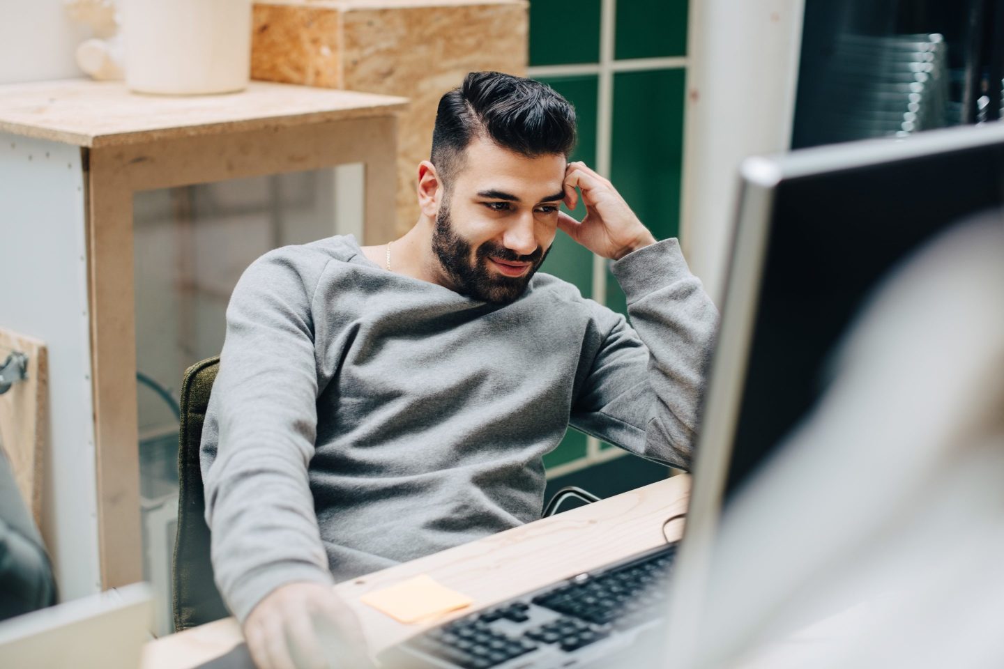 Smiling businessman using computer on desk while sitting in office.