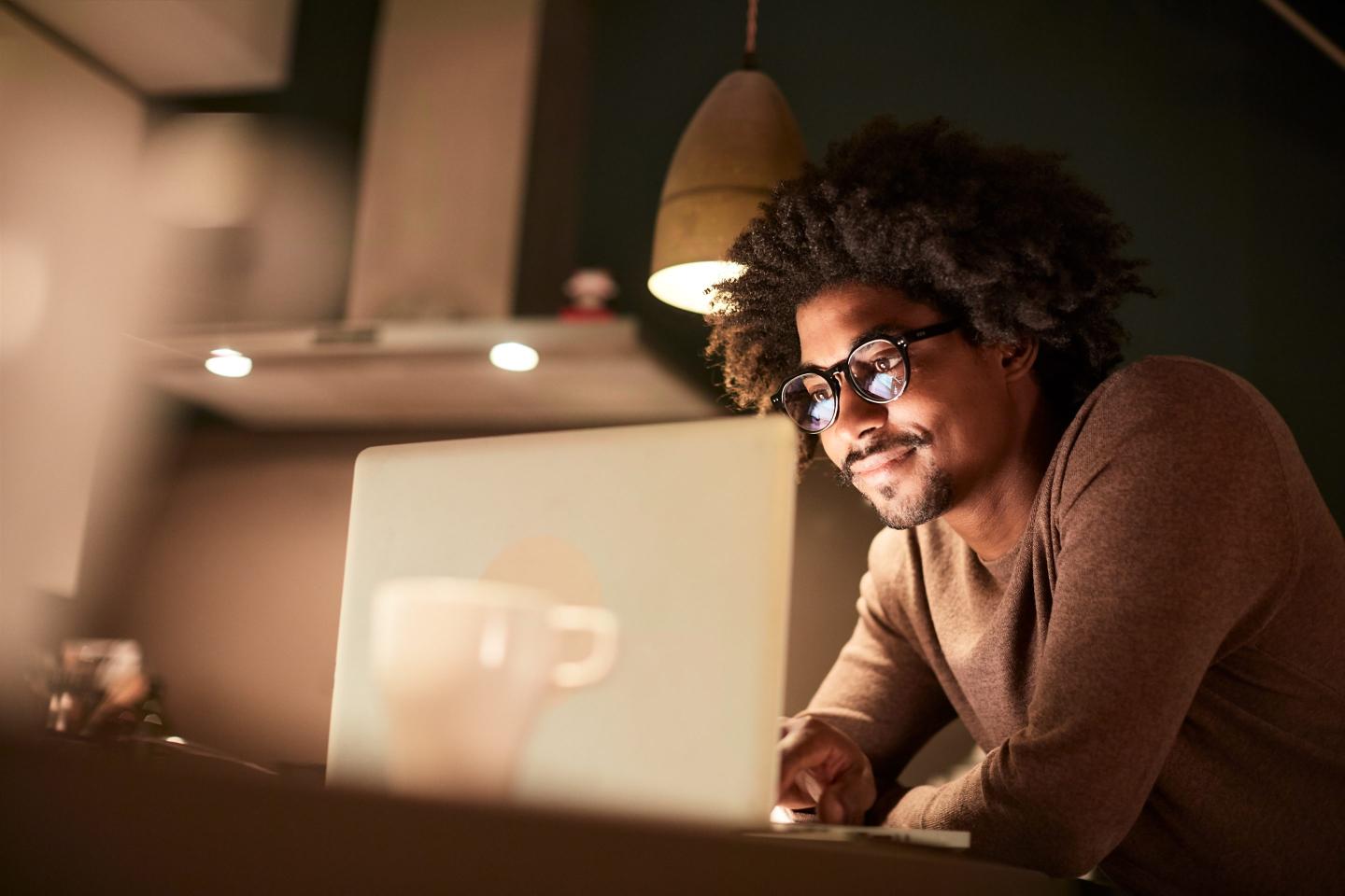 A young man at his computer at night