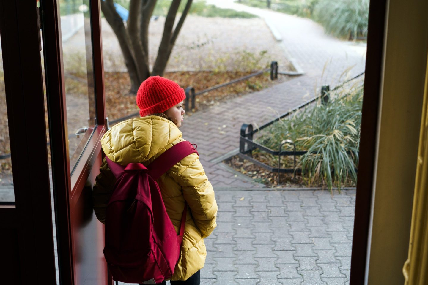 child with backpack leaving home for school