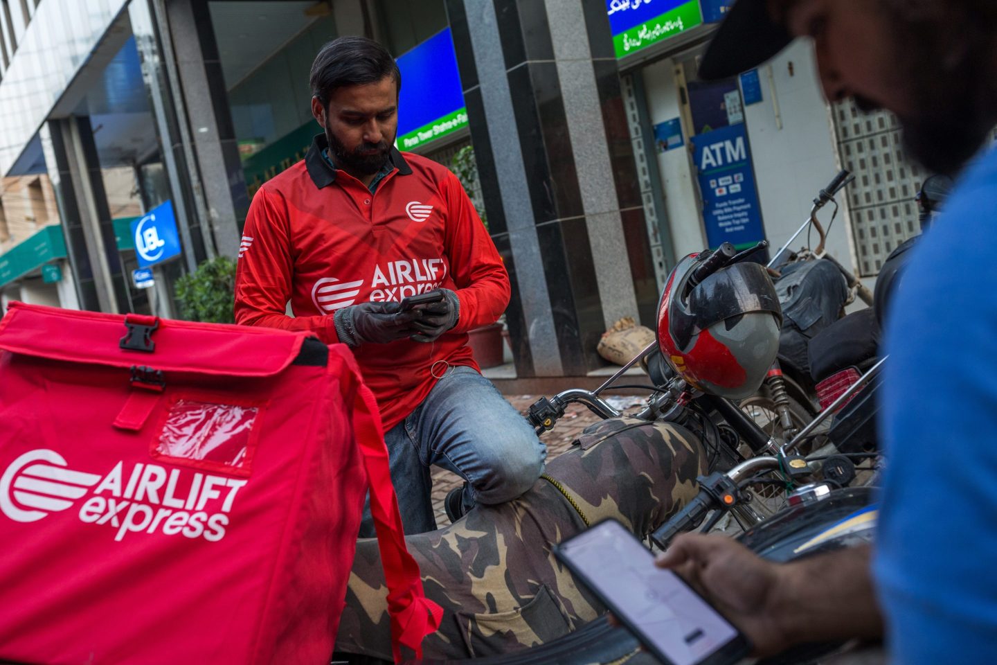 Delivery riders wait to pick up customer orders outside the dark store of Airlift Express, a unit of Airlift Technologies, in Karachi, Pakistan, on Nov. 13, 2021.