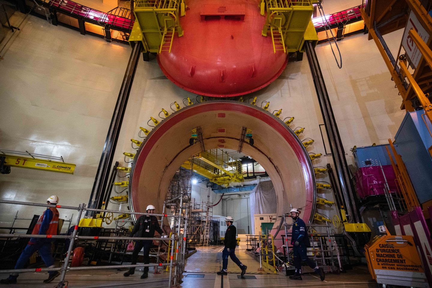 Workers pass next to the reactor building equipment entry at the third-generation European Pressurised Reactor project (EPR) nuclear reactor of Flamanville, Normandy on June 14, 2022.