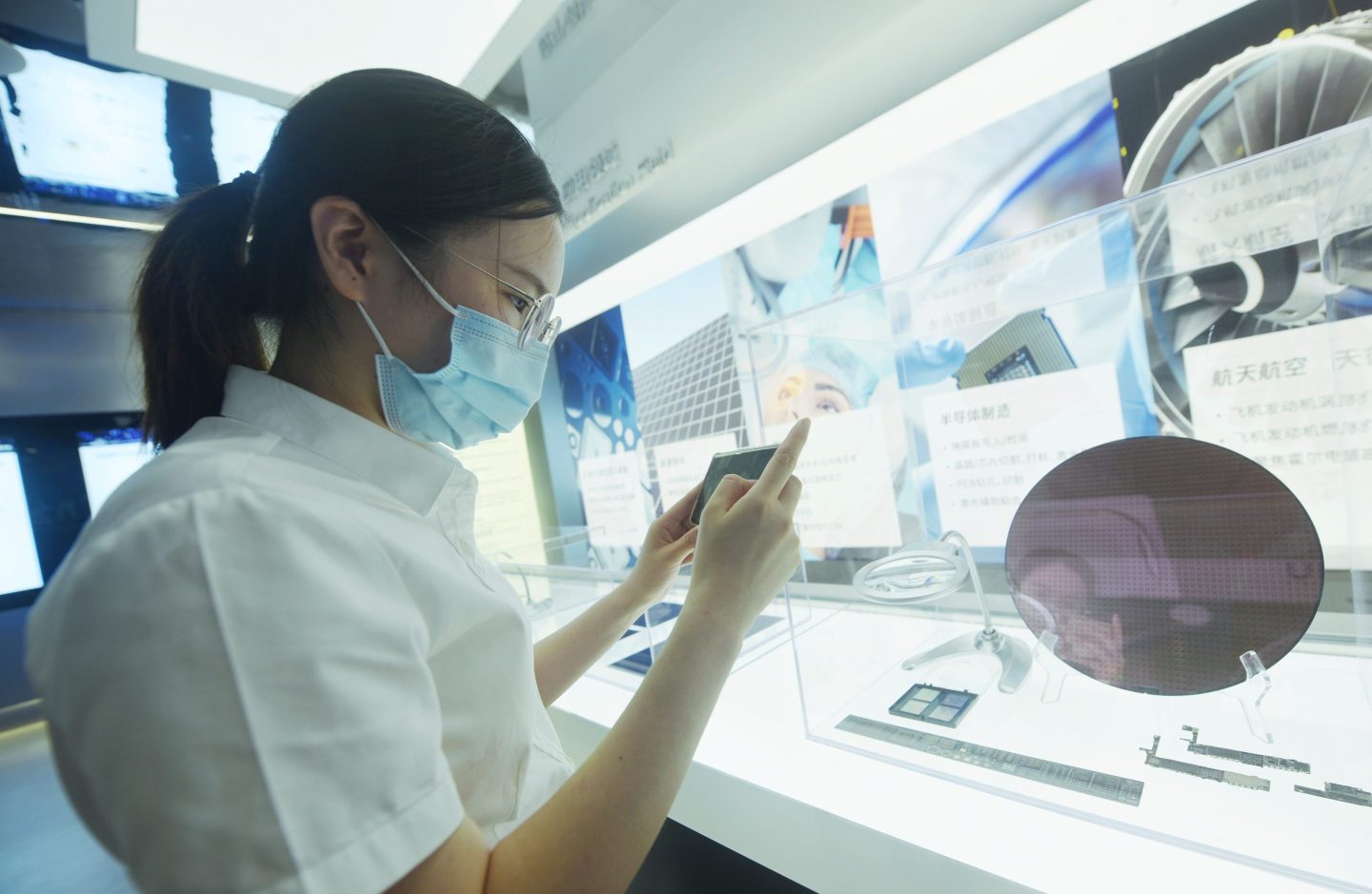 A Chinese woman wearing a mask looks at a semiconductor wafer