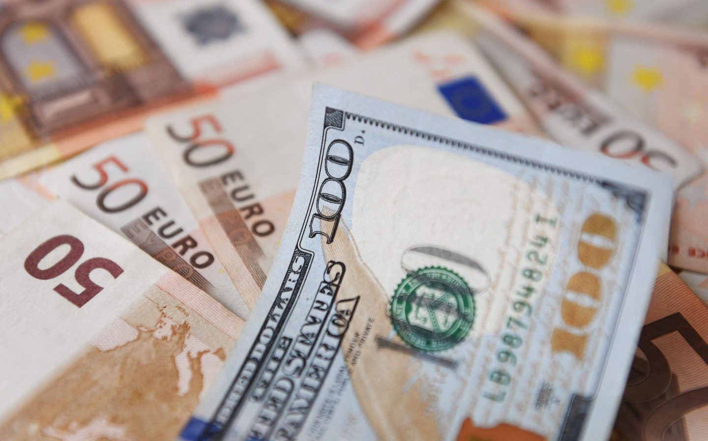 A $100-dollar bill is seen on top of Euro bills