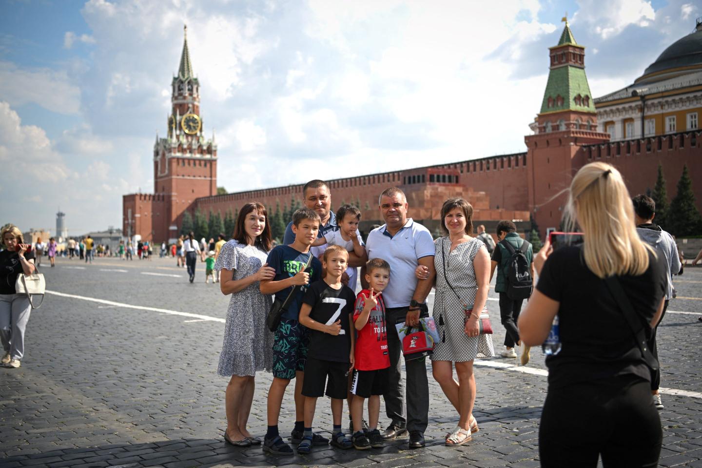 A group of adults and kids pose in Moscow's Red Square for a photo, with one child sporting a t-shirt with the symbol 'Z,' on July 25, 2022.