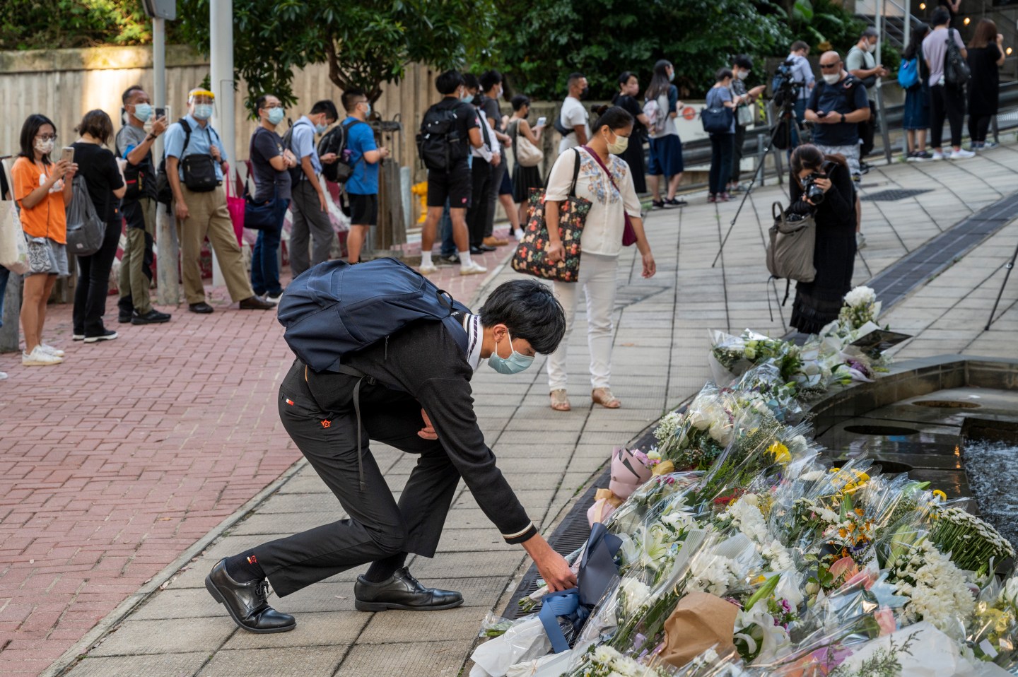 A mourner in Hong Kong kneels to lay flowers in memory of Queen Elizabeth II.