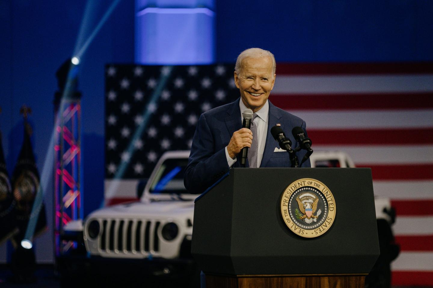U.S. President Joe Biden smiles behind a lectern in front of a U.S. flag