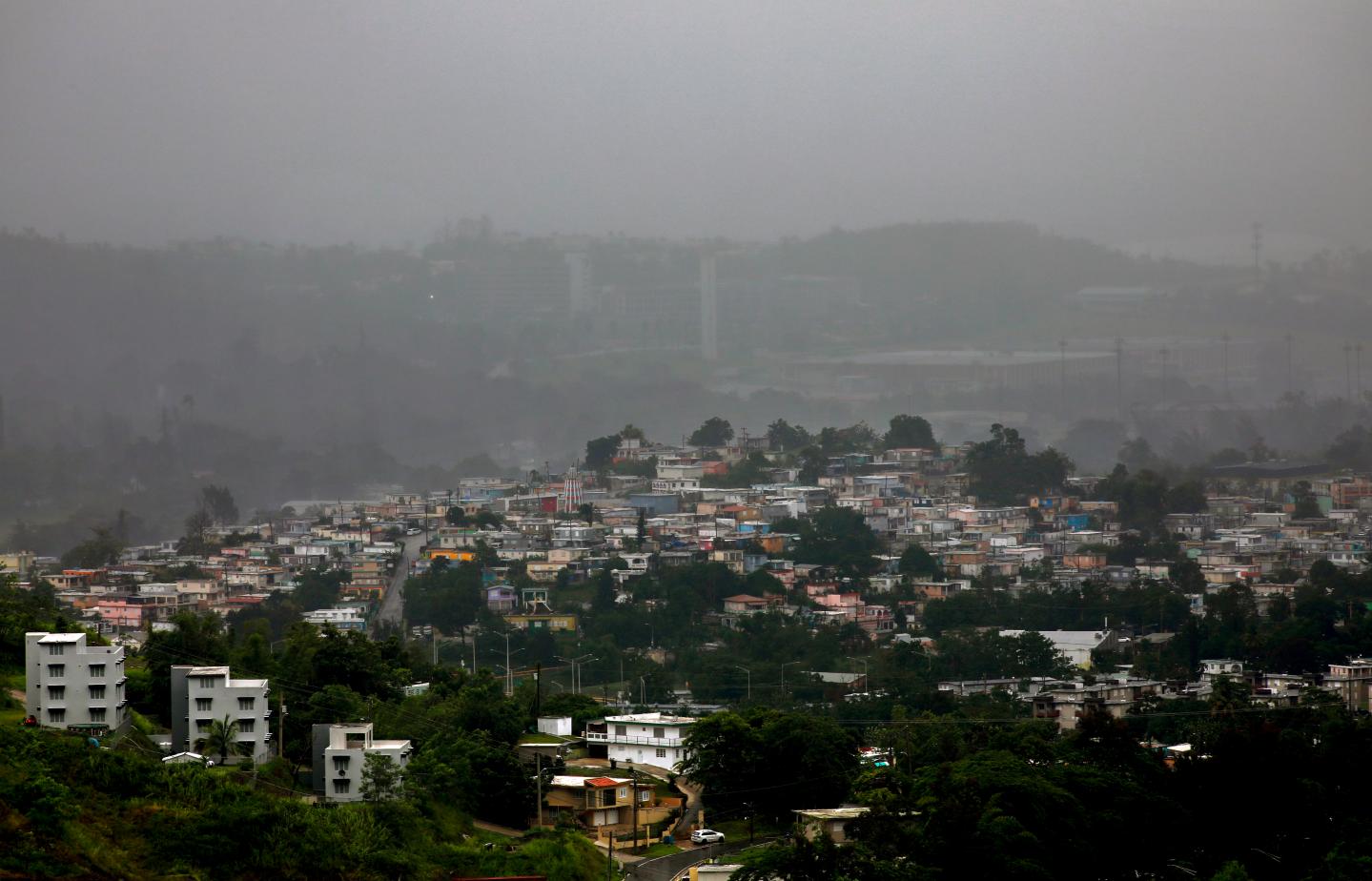 Houses tucked across a mountain rage with a sheet of rain reducing visibility