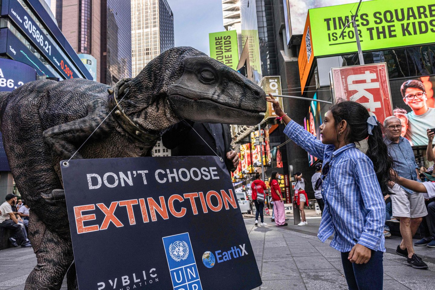 A young girl pets Frankie the Dinosaur, the mascot of the United Nations Development Program's "Don't Choose Extinction" campaign on Sep. 21.