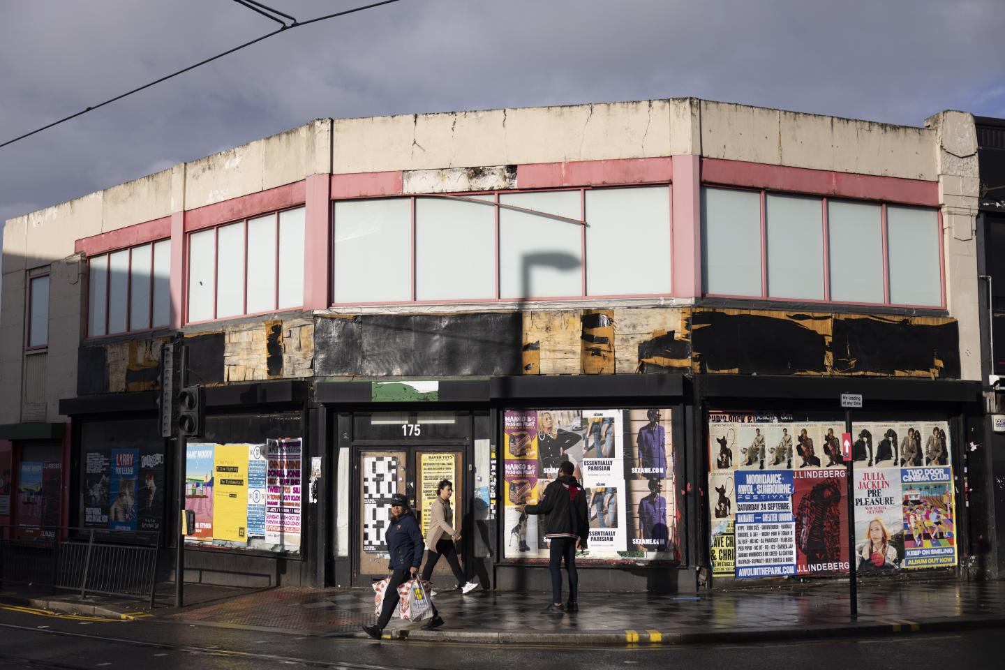 Wide shot of pedestrians passing in front of closed shops in London