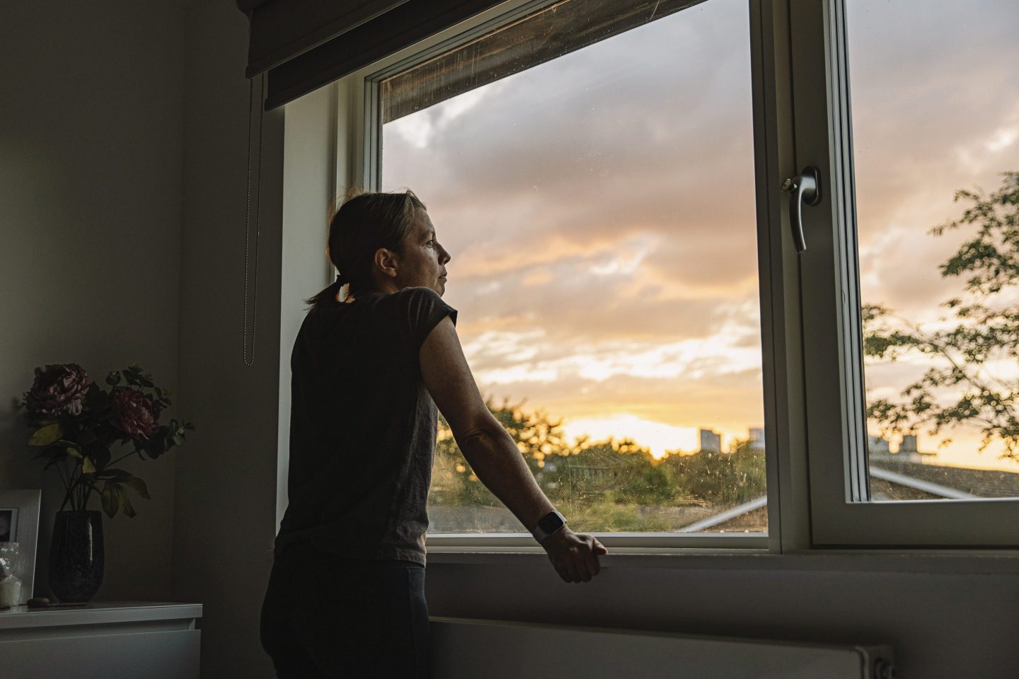 Woman looking out of window at sunset