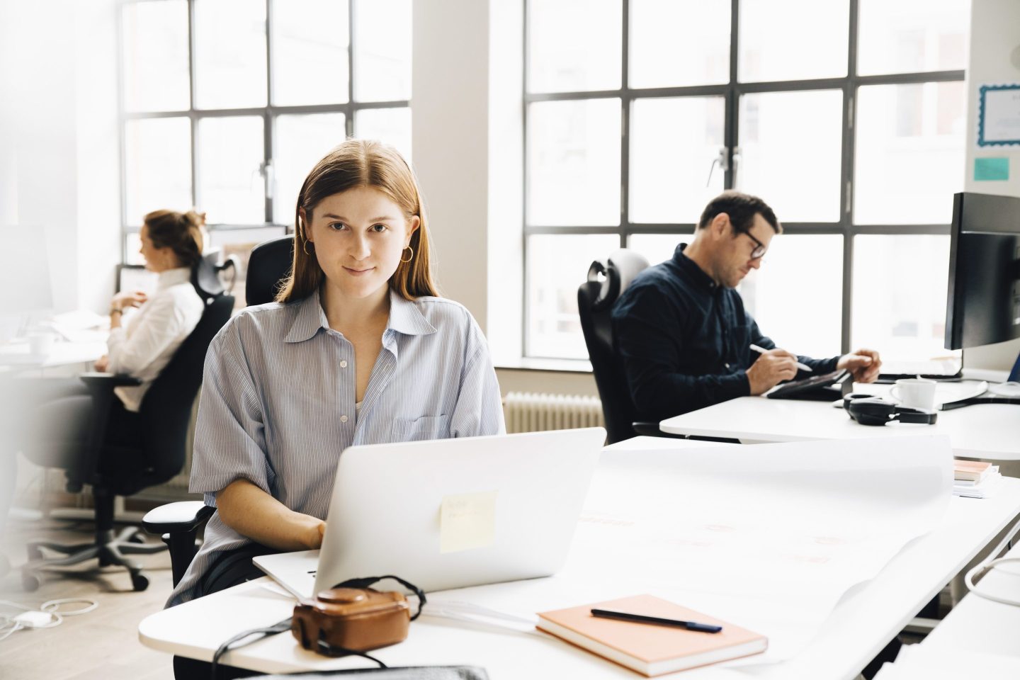 Portrait of businesswoman using laptop at table in office