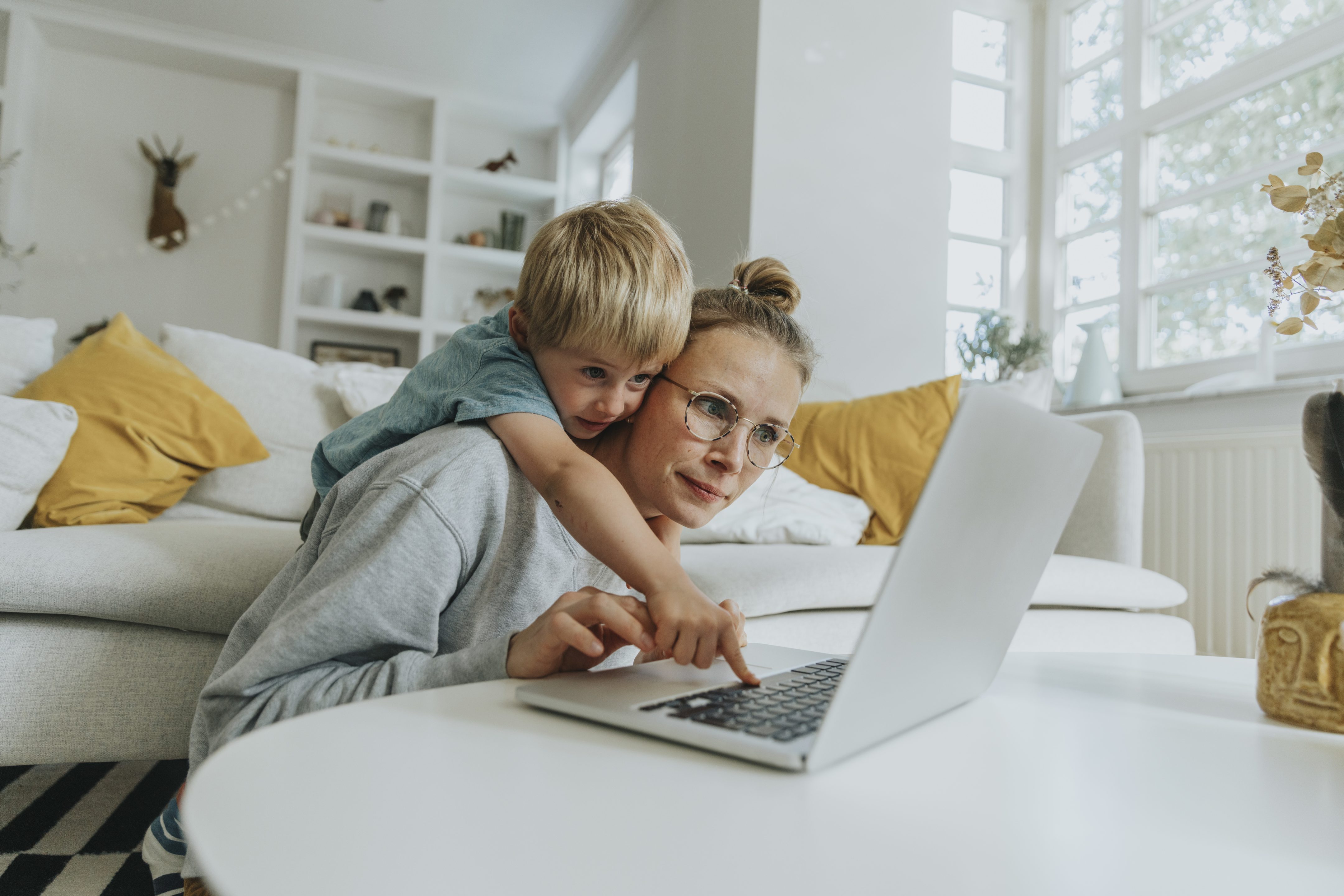Women trying to use laptop while child reaches over.