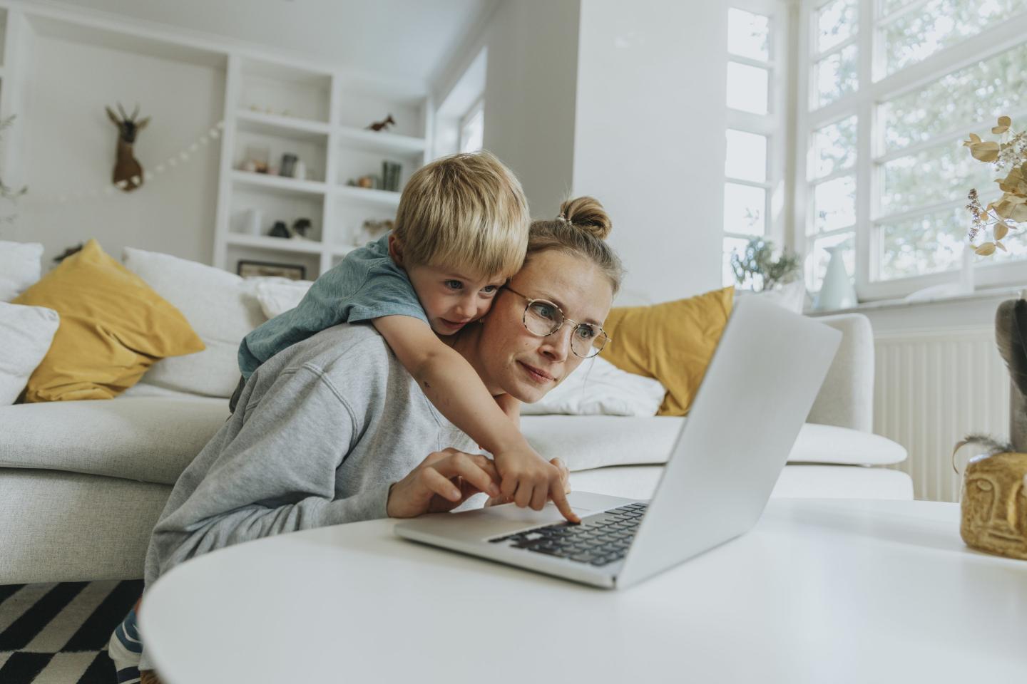 Women trying to use laptop while child reaches over.