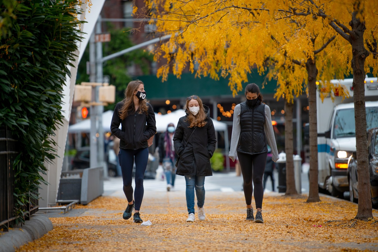 Women wearing masks walk through fallen leaves outside NYC AIDS Memorial Park on Oct. 25, 2020, in New York City.