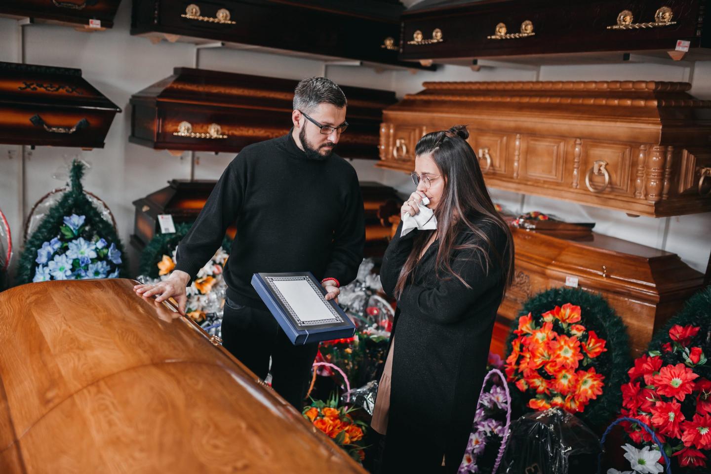 Undertaker showing coffins to a widow