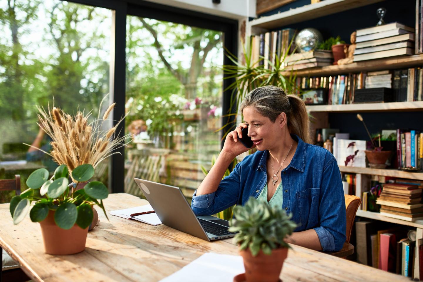 Businesswoman using mobile phone in front of laptop