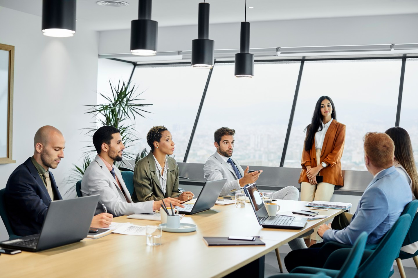 A group of executives sit around a long table conducting a meeting.
