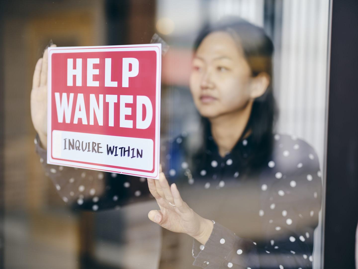 Business Owner Putting Up Help Wanted Sign