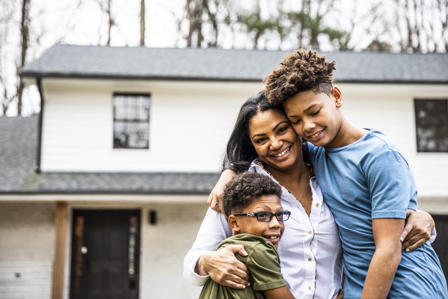 Portrait of mother and sons in front of residential home