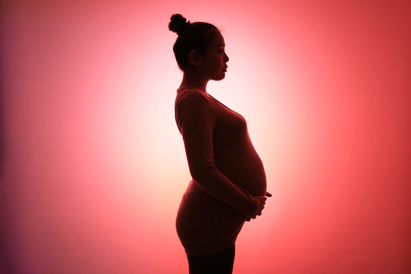 Portrait of a pregnant woman in front of a red background.
