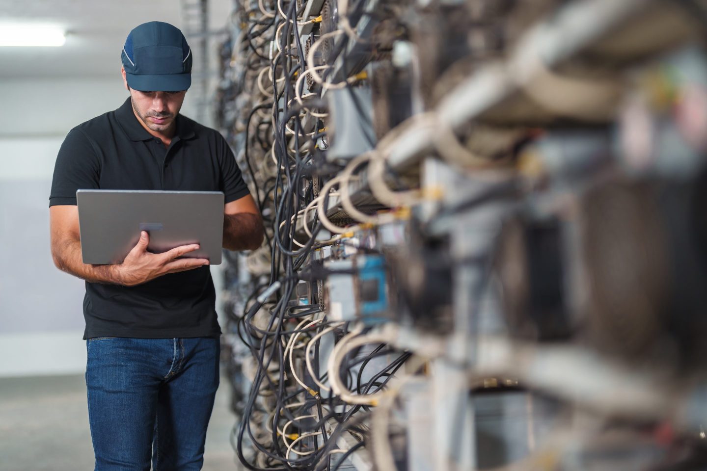 Professional engineers carrying the laptop working in crypto mine.