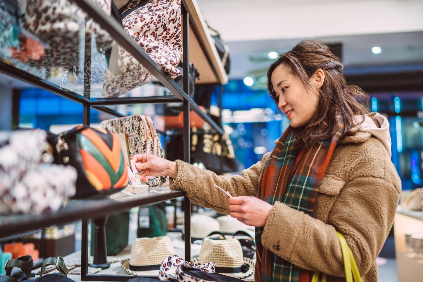 Young cheerful Asian woman shopping for accessories