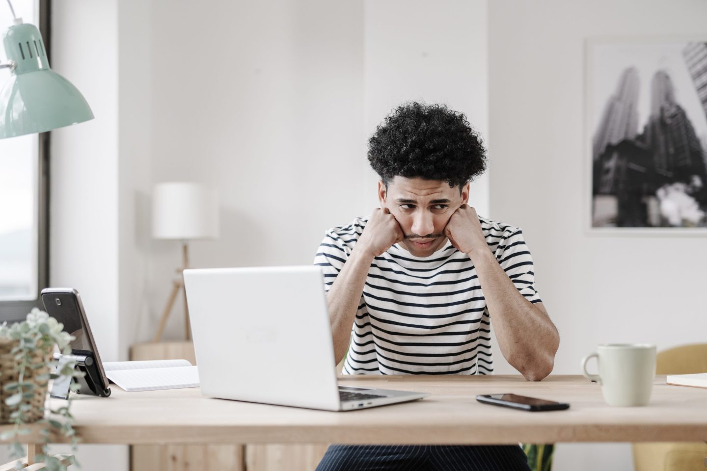 Picture of a frustrated young man next to his laptop