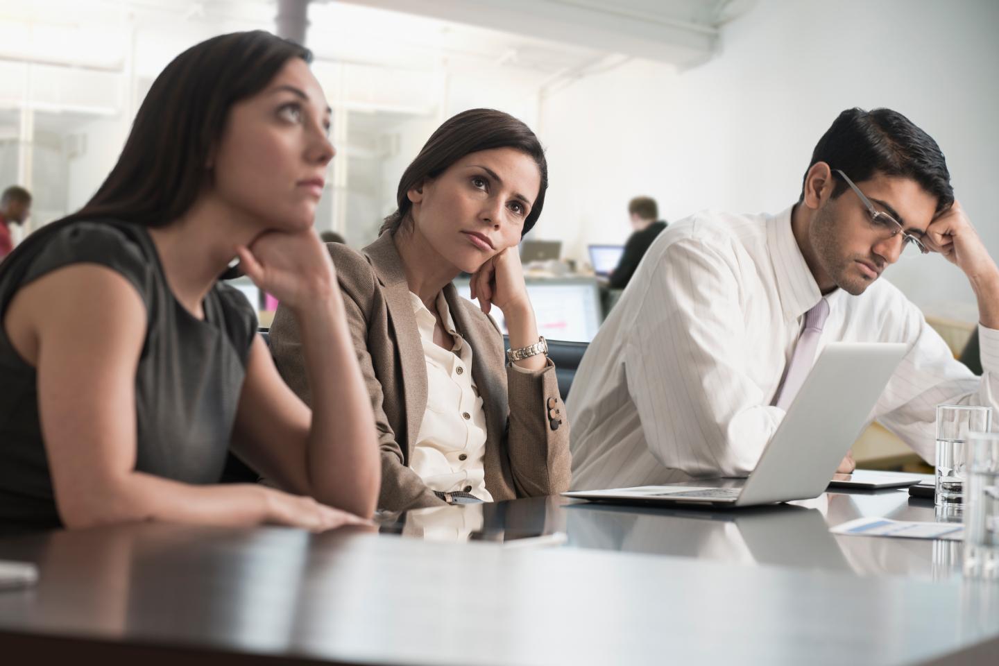 Office workers look bored in a meeting.