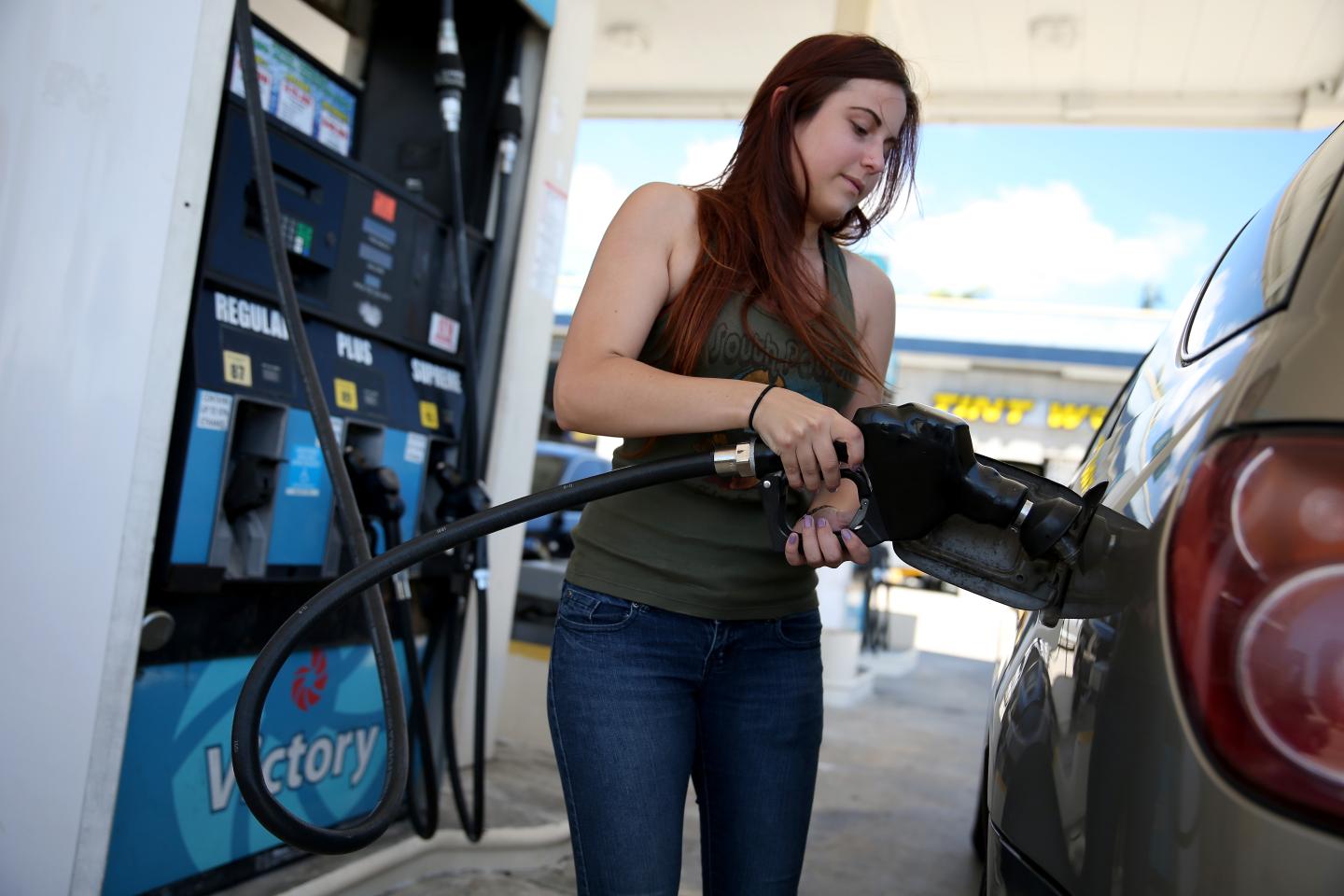 A woman pumps gas at a gas station.
