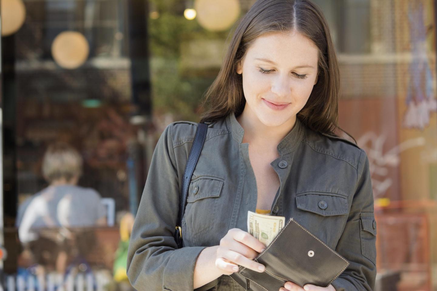 A woman pulls money out of her wallet