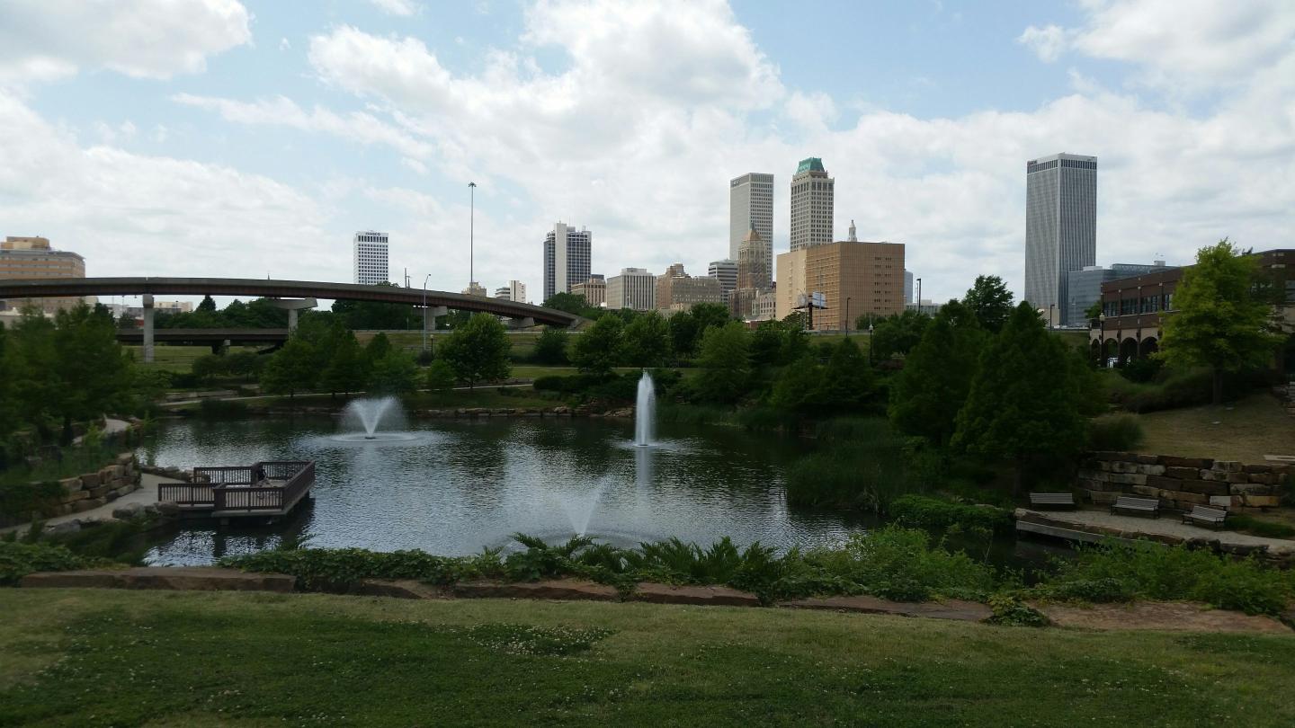A sunny day with a park and water features in front of buildings in the distance