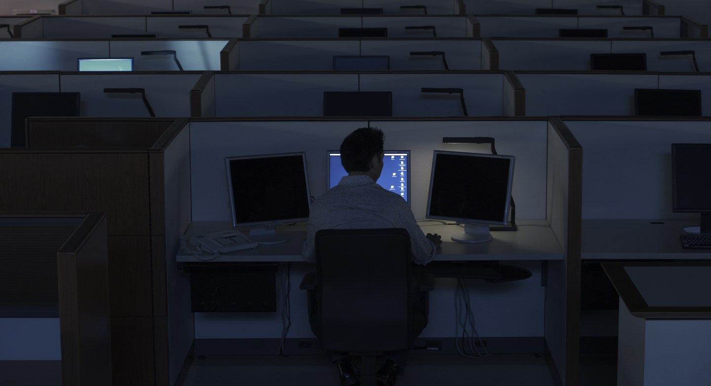 Single employee at a cubicle alone in a dark office