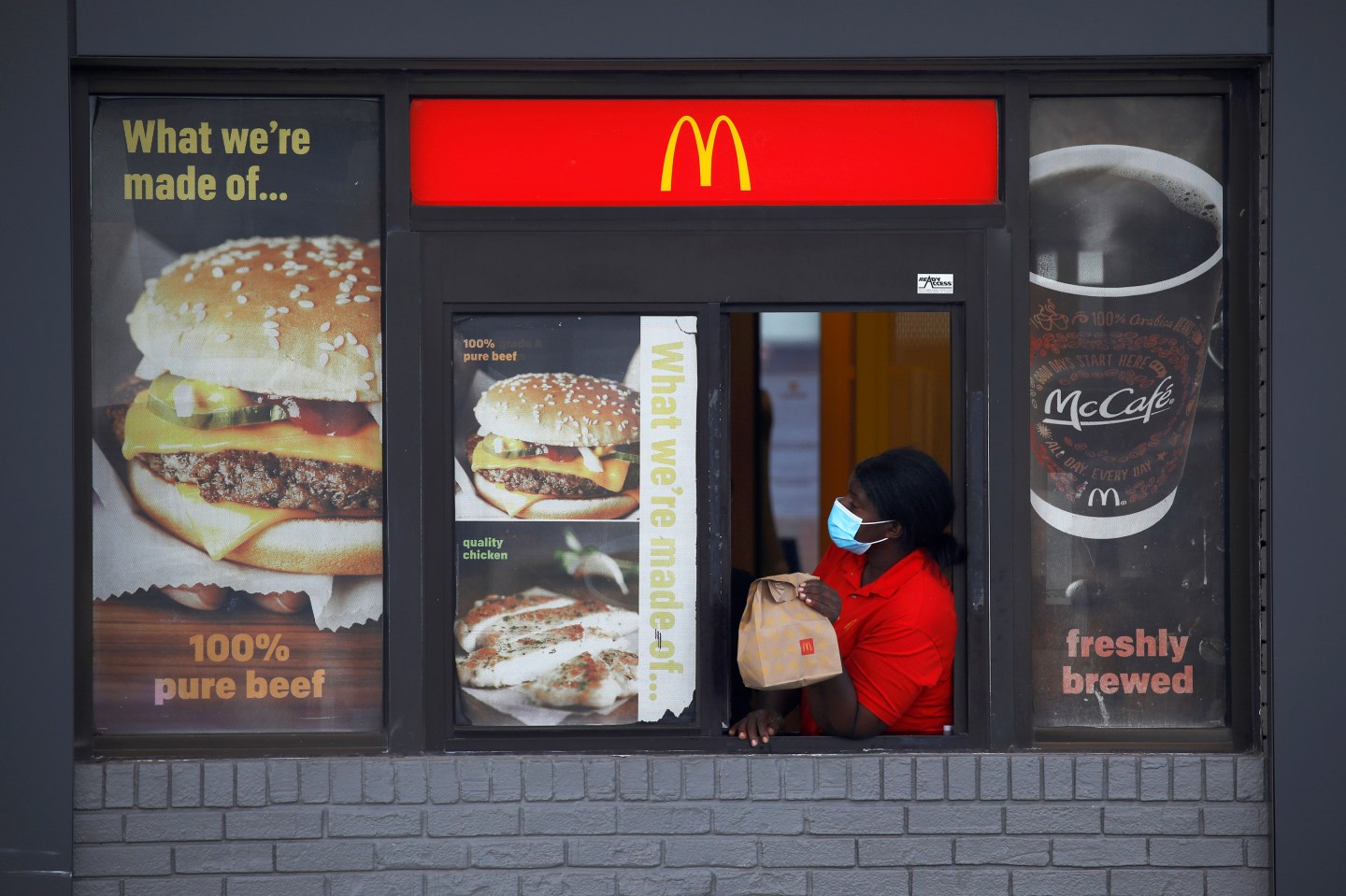 An employee waits for a customer to pickup food in the drive-thru window of a McDonald's.
