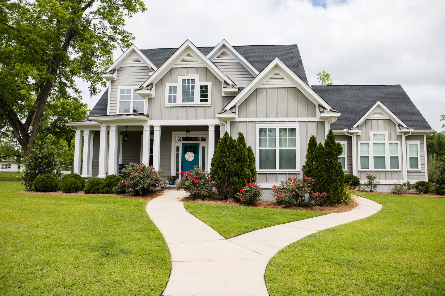 Suburban cottage style house with a green yard and nice landscaping.