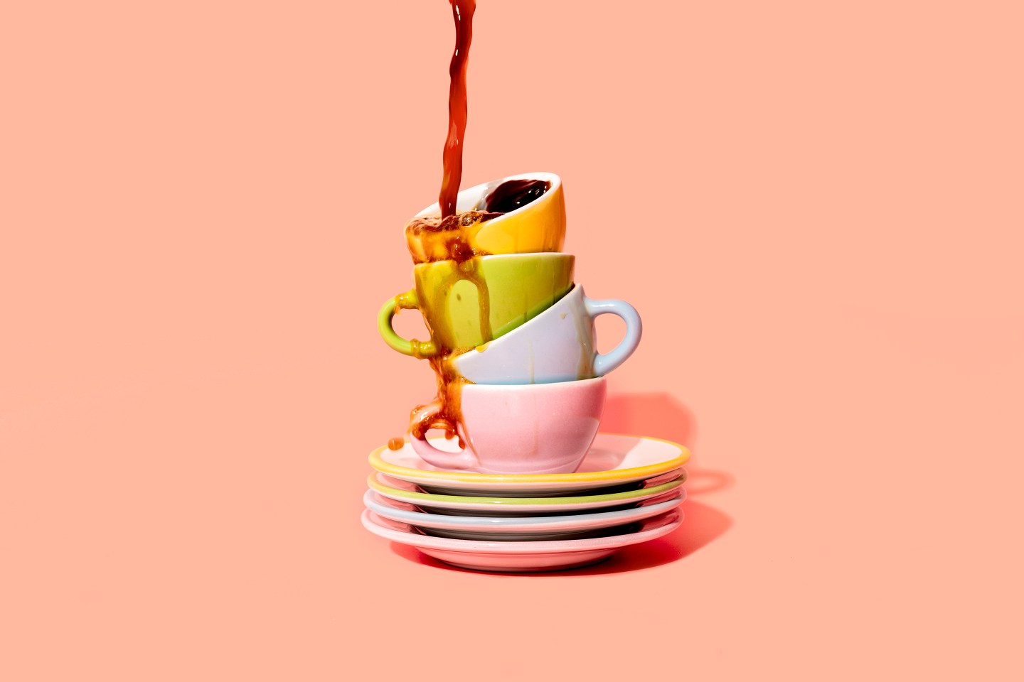 Studio shot of coffee pouring on stack of plates and coffee cups.